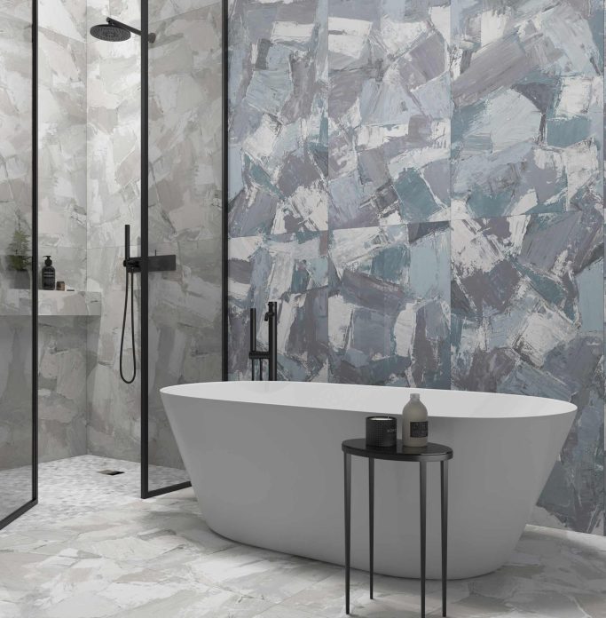 Baño moderno con bañera blanca, ducha acristalada y paredes de azulejos en tonos grises.