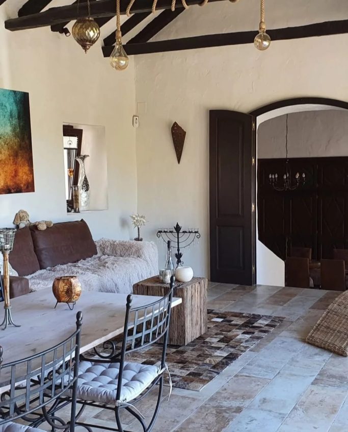 Sala luminosa con sofá, mesa de café, decoraciones artísticas y puertas de madera.