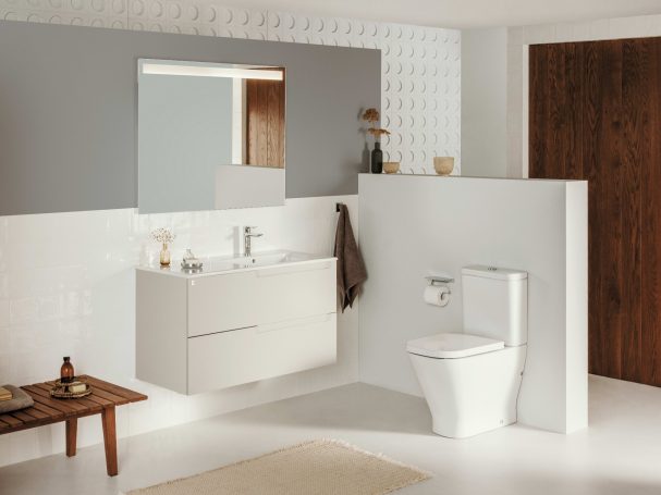 Baño moderno con muebles blancos, lavabo, espejo y sanitario. Suelo claro y pared de madera.