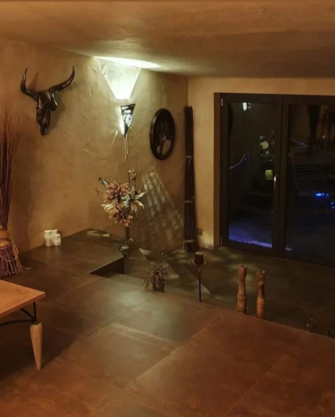 Interior de una habitación con decoración rústica, plantas y luz suave.