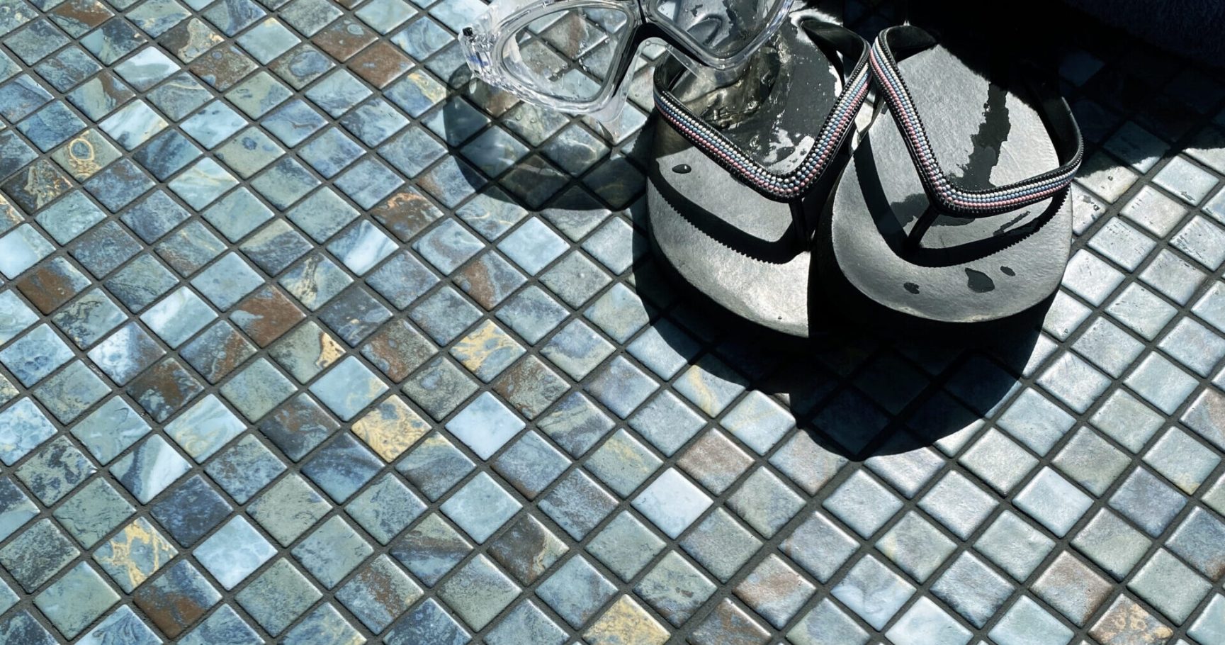 Chanclas sobre un mosaico de azulejos en tonos azules y marrones.