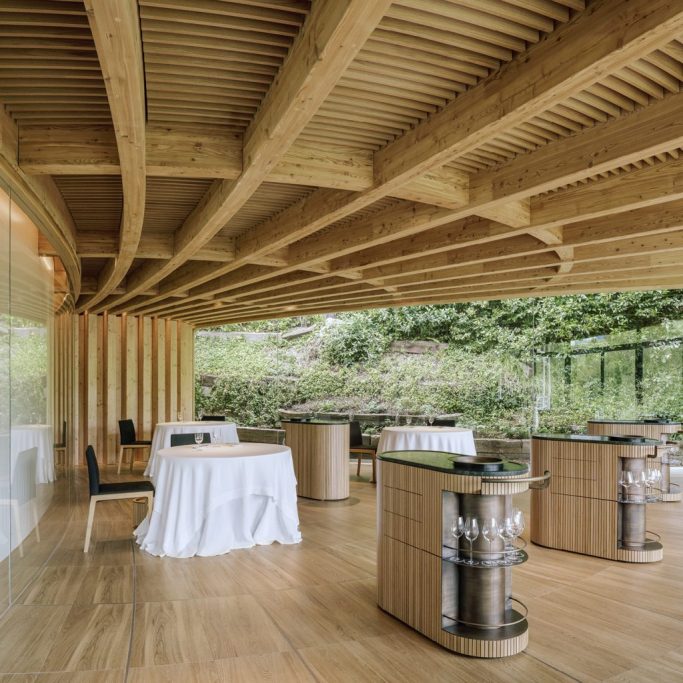 Interior de un restaurante moderno con mesas, sillas y estructuras de madera.