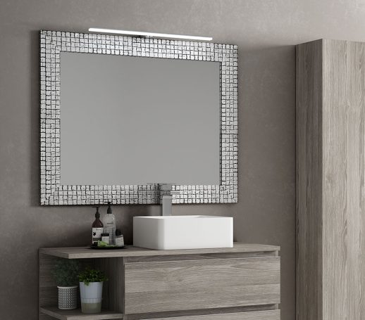 Espejo rectangular con marco decorativo sobre un mueble de baño moderno.